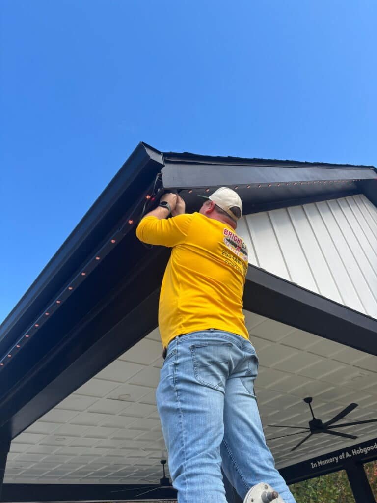 Man on a ladder installing holiday lighting